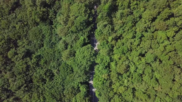 Aerial View Flying Over Old Patched Two Lane Forest Road With Cars alt