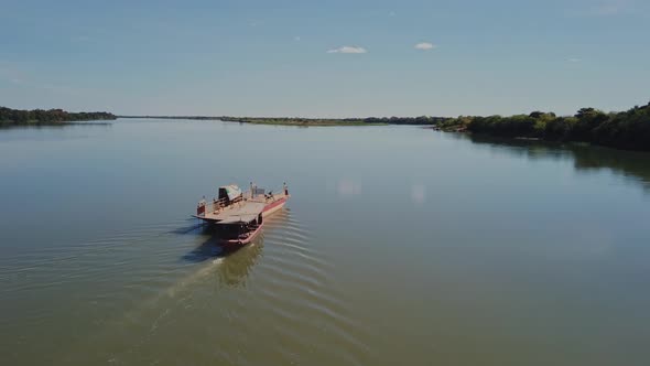 Small empty ferry sails across the Sao Francisco River in rural Brazil. Aerial drone shot, flyover. alt