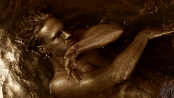 An Ethnic Northern Shaman Performs the Ritual Lying in an Ode with Gold on His Skin alt