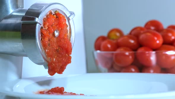 Tomatoes is twisted through a meat Grinder to Prepare Tomato paste alt