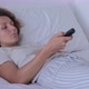 A Bored Woman on the Bed Holds a TV Remote Control in Her Hands - VideoHive Item for Sale