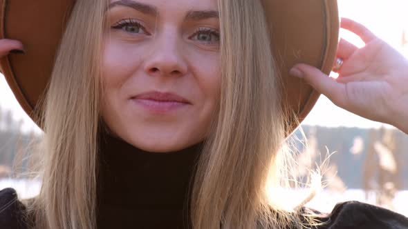 European Blonde Woman Smiling with Beige Hat in Black Sweater in the Countryside alt