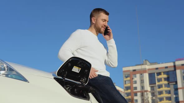 A Male Driver Connects an Electric Car to the Power System to Charge the Car Battery and Controls alt