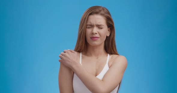 Sport Trauma. Studio Shot of Young Lady Suffering From Shoulder Pain, Blue Background alt