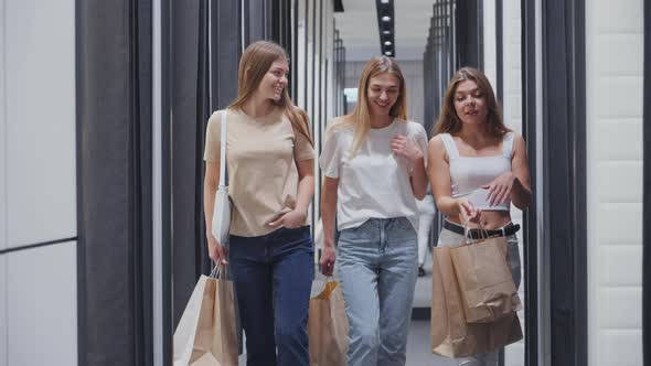 Happy Women with Purchases Walking Past Dressing Rooms alt