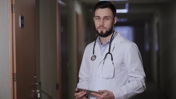 Portrait of Doctor with Tablet Standing in the Hallway alt