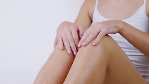 Woman Applying Moisturizer Cream or Body Lotion on Her Legs