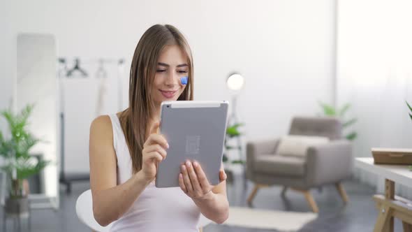 Portrait of Young Cute Woman Getting Good News From Her Tablet Sitting at Home alt