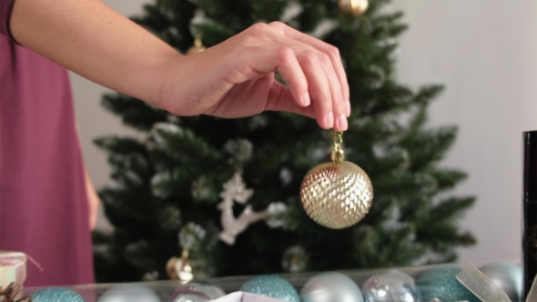 Young Woman Decorating Christmas Tree. Camera Follow The Hand With Toy.