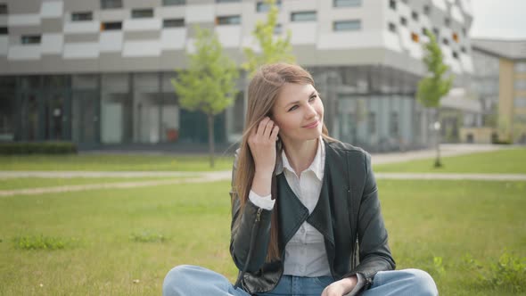 Attractive Female Student Sitting on the Grass Near School or College or Office alt