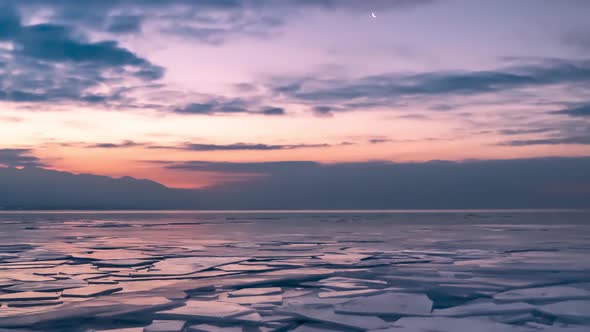 Rafted ice on a frozen lake, mountains and cloudscape - time lapse zoom out alt