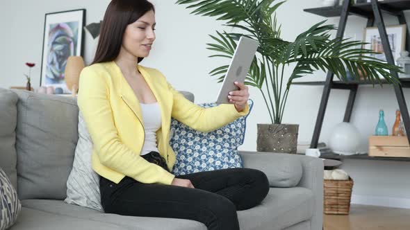 Online Video Chat on Tablet by Beautiful Woman Sitting on Sofa alt