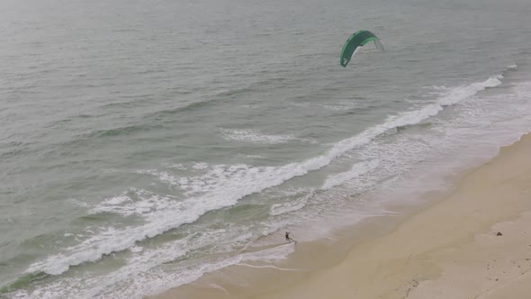 Wind surfer riding up onto the beach and jumping off the board on a beach in Sierra Leone Africa. alt