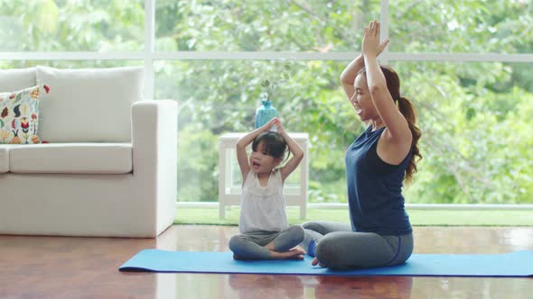 Young mother applauded to her daughter while teaching yoga