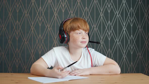 Homeschooling Online By Videocall Redhaired Teen Boy Sitting at Workplace in Living Room and Uses a alt