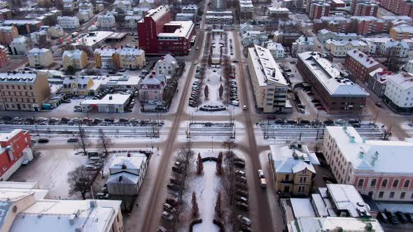 Aerial forward tilt-up reveal view of snowy Sundsvall Swedish cityscape at dusk, Sweden alt