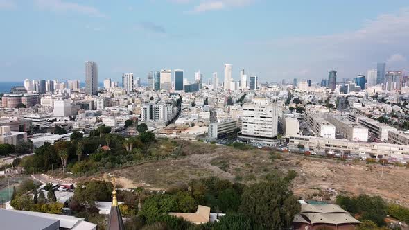 Aerial downward shot revealing a church steeple in front of city buildings view, park and sky, on a alt