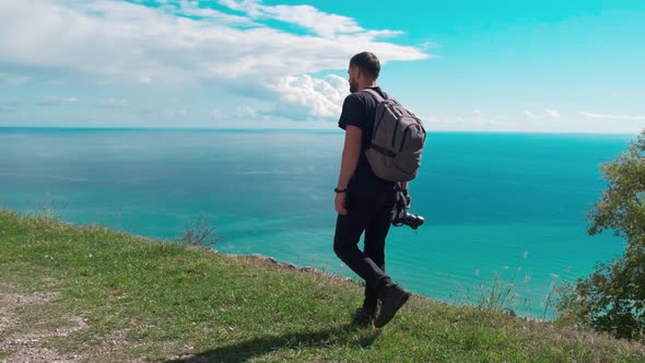 Adventure, Travel, Tourism, Hike and People Concept - Hiking Man with Backpack Looking at Sea or alt