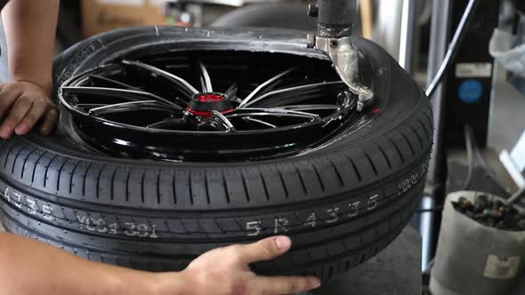 Car mechanic replace tire on wheel in auto repair service.