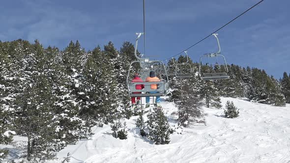 Smooth traveling of the route between snowy trees of the Baqueira Beret lift, in Pyrenees. On a sunn alt