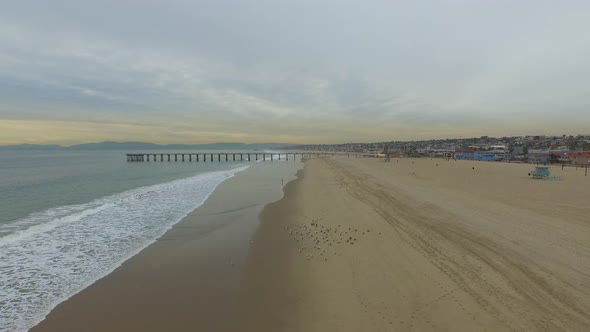 Aerial shot of beach city and waves breaking on the beach. alt