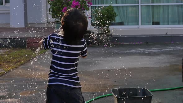 Cute Asian Boy Has Fun Playing In Water From A Hose Outdoors Slow Motion alt
