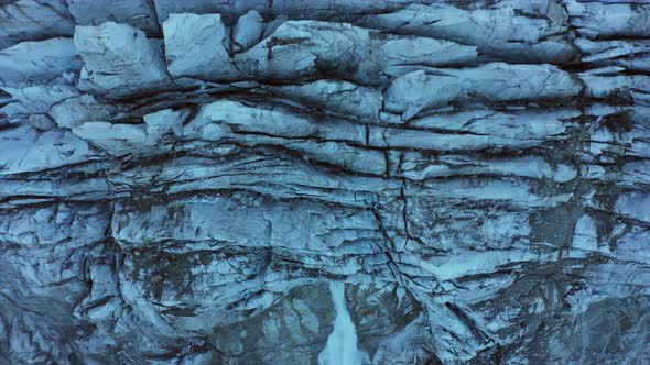 Top Aerial View of the Mountain Glacier with Waterfall Below the Glacier