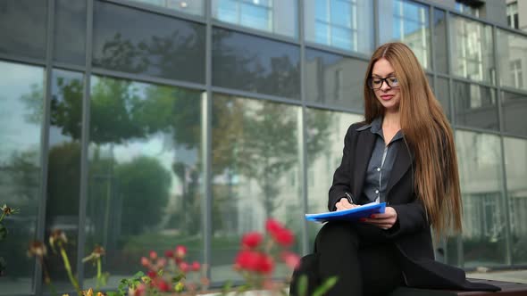 Businesswoman Signing Documents in a Quiet Street alt