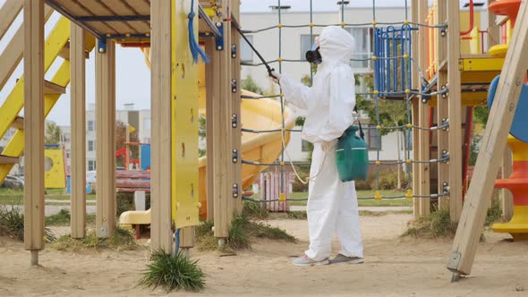 disinfector in protective suit and respirator is treating playground  alt