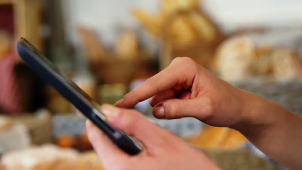 Mid section of woman using digital tablet at bakery section alt