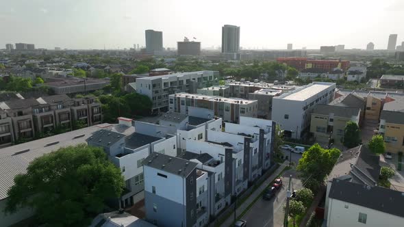 Residential homes in urban city setting. Aerial orbit reveals downtown skyscrapers in USA. alt