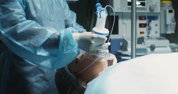 The Anesthesiologist Puts a Mask on a Young Woman Patient alt