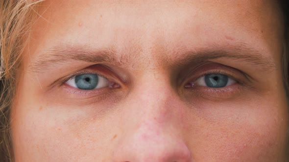 Close up of a young male eyes. Blue eyes of a caucasian man looking at camera.