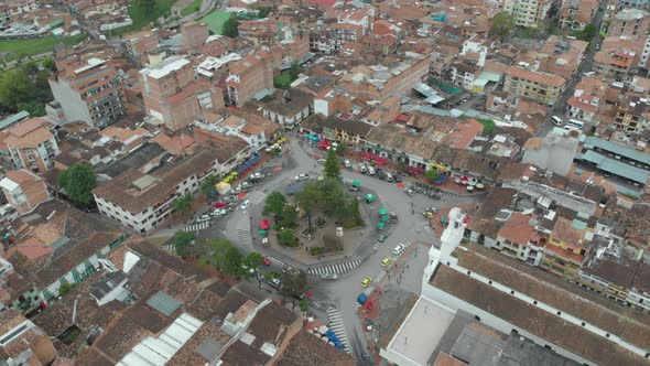 Cars Driving Around Public Park Surrounded With Typical Buildings In El Peñol, Antioquia, Colombia. alt
