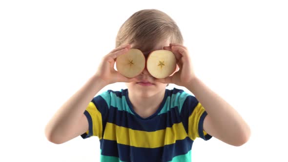 Little Boy Posing in Studio on a White Background with Cut Apple Instead of Eyes