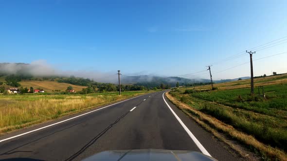 POV shot of driving a car on the road along the forest and mountains. Traveling in the summer by car