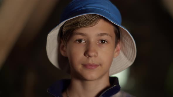 Portrait of a Happy Boy in a Blue Hat Looking at the Camera and Smiling Camera Moves Away
