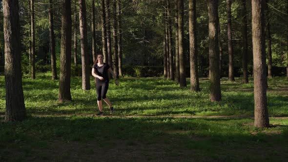 Woman in a Black Uniform in the Morning Goes in for Sports in the Park, Forest