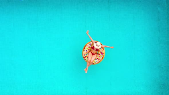 Aerial View of a Woman in Red Bikini Lying on a Donut in the Pool alt