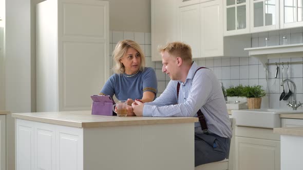 Mother and Grown Son Watching Photos on Tablet PC alt