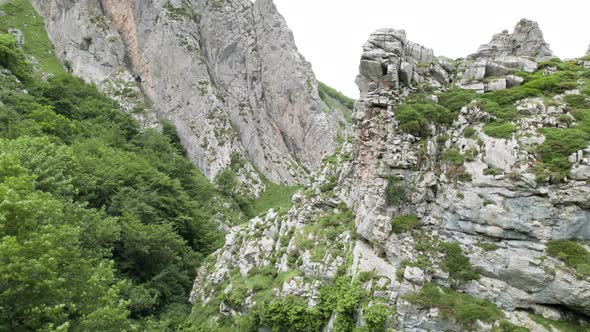 Drone ascent revealing rocky canyon in green natural valley. Asturias, Spain. alt