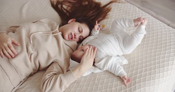 Young Mother Lying On The Bed With The Baby