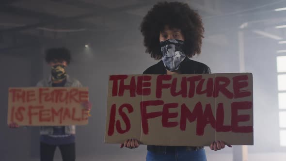 Mixed race man and woman wearing face masks holding protest signs alt