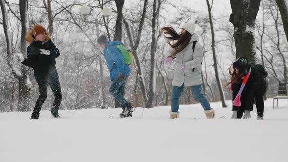 Children Have Fun Throwing Snow at Each Other in City Park alt