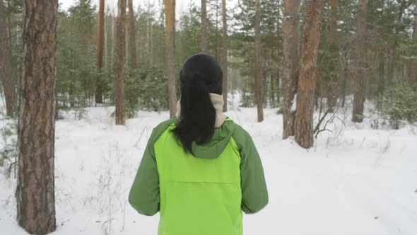 Rear View of Woman Jogging in Forest in Winter alt