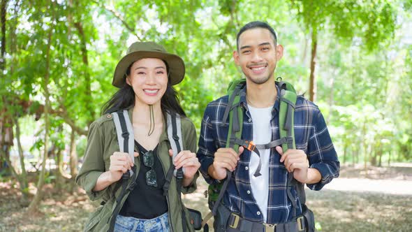 Portrait of Asian man and woman backpacker travel in forest together. alt