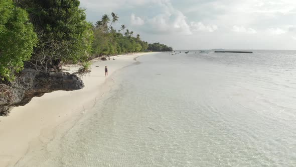 Aerial: Flying over tropical beach turquoise water coral reef , Indonesia alt