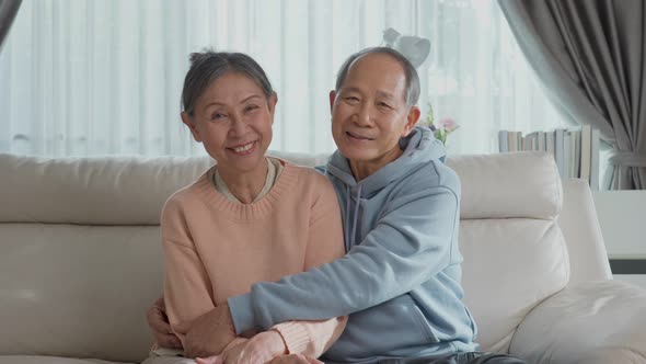 Portrait of Asian happy senior elder mature couple sit on sofa and smiling in living room at home. alt