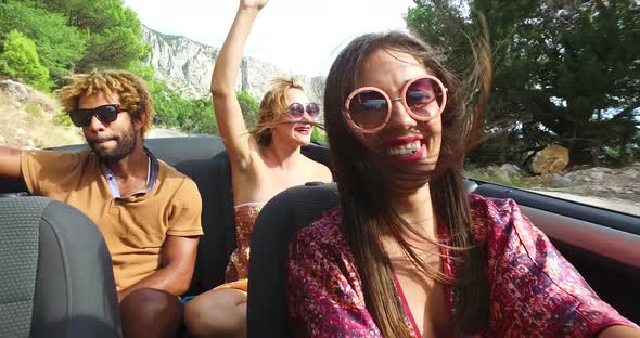 Young cheerful couple singing while driving in convertible alt