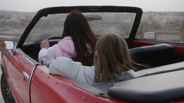Woman And Girl Sitting in Retro Red Car Cabriolet on Nature Enjoying the View